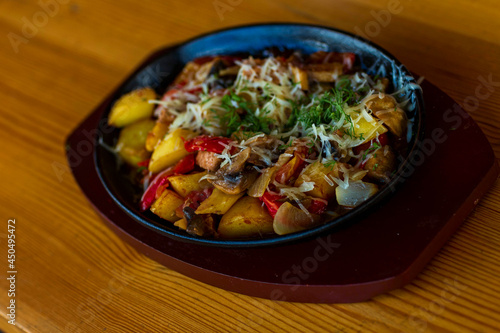 hot frying pan with potatoes,vegetables,mushrooms and meat, seasoned with herbs