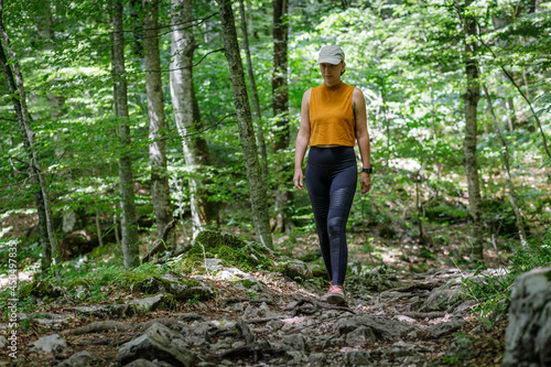 Young sporty woman walking on trail in the forest.