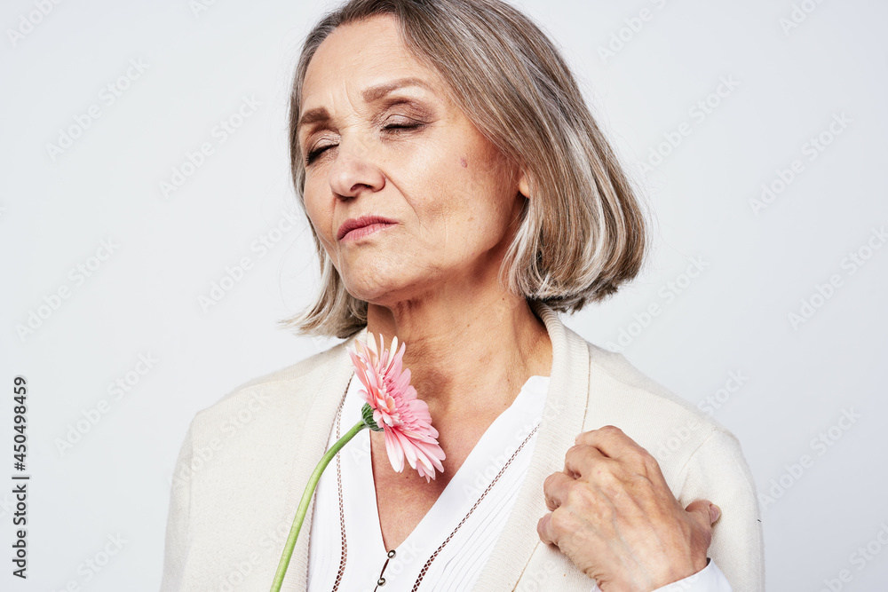 elderly woman in a robe holding a flower gift light background elderly woman in a robe holding a flower gift light background