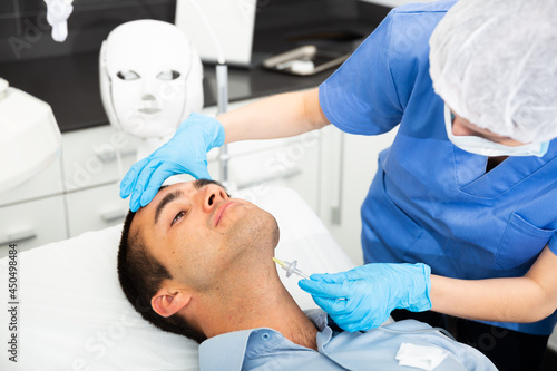 Male client getting carbon dioxide injections for face skin rejuvenation in clinic of aesthetic cosmetology.
