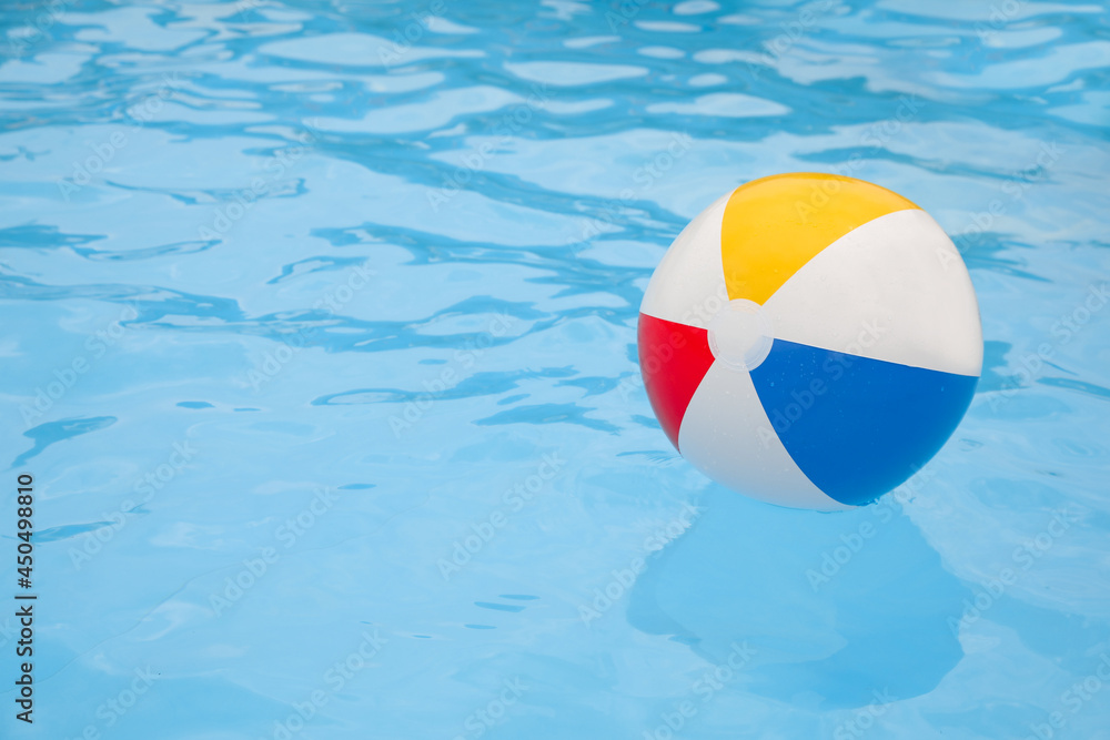 Inflatable colorful beach ball floating on water in swimming pool, space for text
