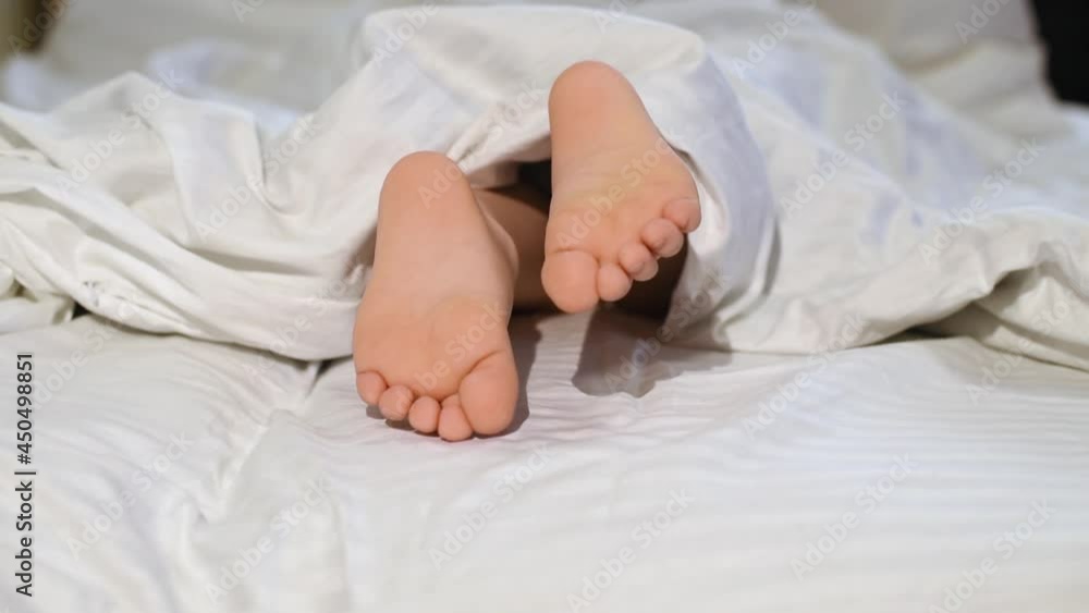 Child feet peeking out from under the blanket. Morning concept. Child feet peeking out from under the blanket. Morning concept.