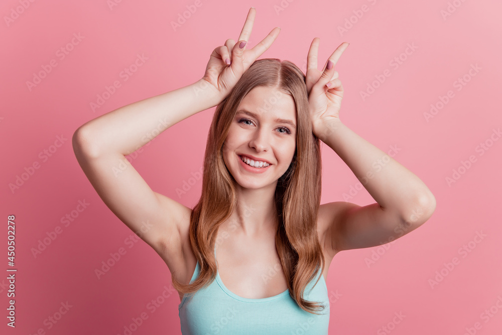 Portrait of funny childish positive lady make bunny ears fingers head on pink background Portrait of funny childish positive lady make bunny ears fingers head on pink background