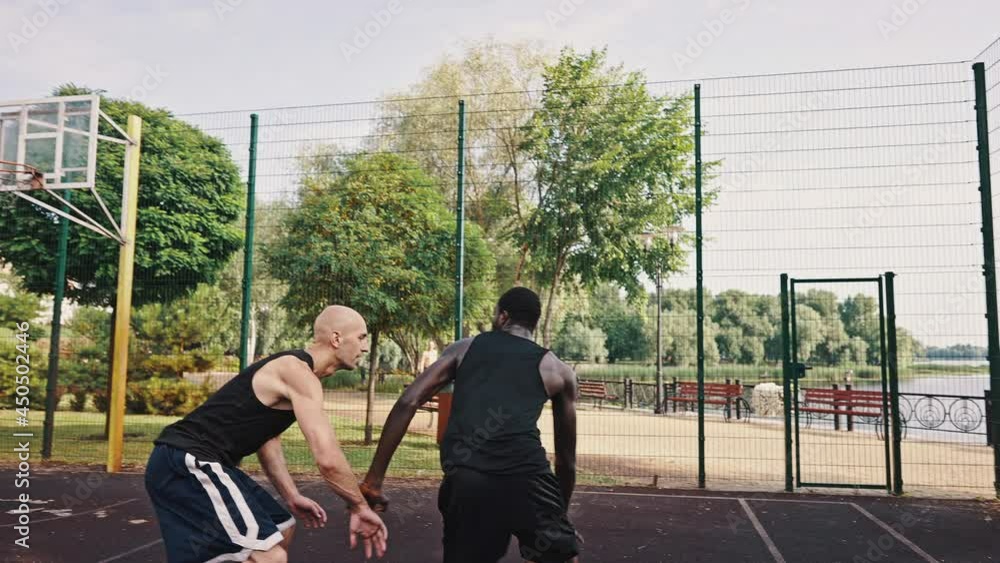 Playing man-to-man at basketball game. African American and Caucasian athletes are trying to dribble, are fighting for the ball Playing man-to-man at basketball game. African American and Caucasian athletes are trying to dribble, are fighting for the ball