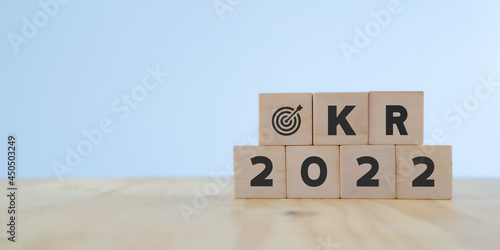 OKRs : Objective key result in 2022 concept. Word OKR , year 2022 and target icon on wooden cubes .standing on table with beautiful white background. Business plan for the next year. Copy space.