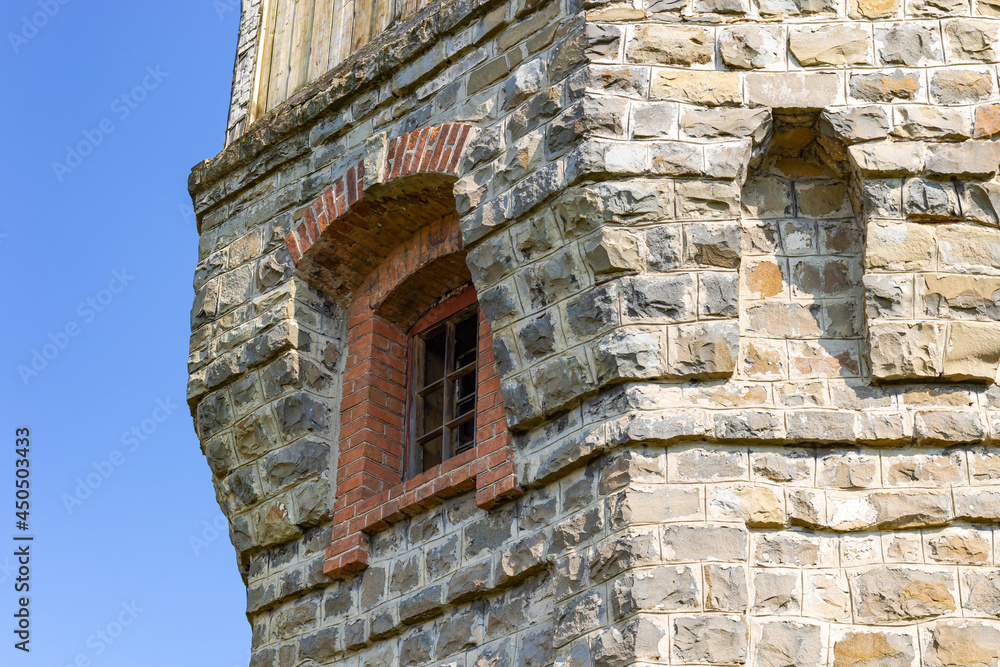 The upper part of an ancient watchtower made of stone blocks and wood paneling with windows against the blue sky on a bright sunny summer day. Close-up The upper part of an ancient watchtower made of stone blocks and wood paneling with windows against the blue sky on a bright sunny summer day. Close-up