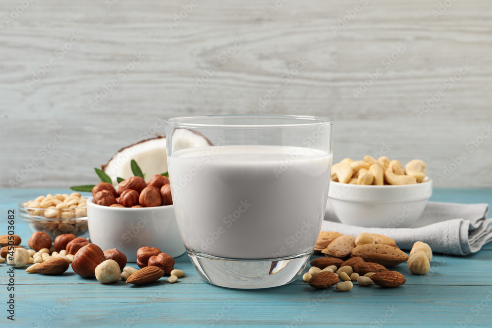 Vegan milk and different nuts on light blue wooden table Vegan milk and different nuts on light blue wooden table