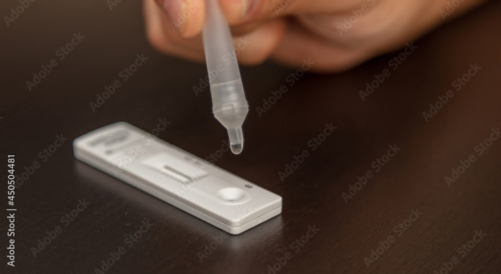 Man performing a self test. Rapid antigen diagnostic test kit with nasal swab and tube. Man performing a self test. Rapid antigen diagnostic test kit with nasal swab and tube.