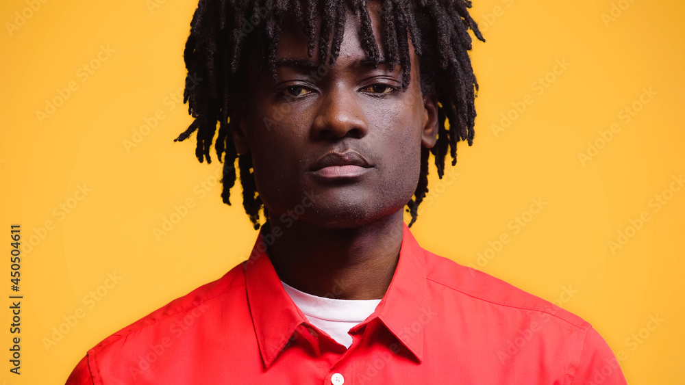 Portrait of african american man with dreadlocks in red shirt isolated on yellow Portrait of african american man with dreadlocks in red shirt isolated on yellow