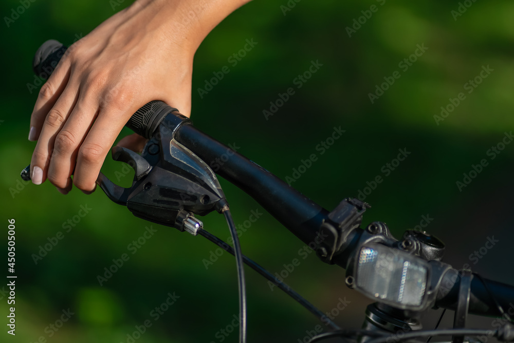 Woman's hand pressing the brakes of a mountain bike in the bright sunlight of a summer day close-up with copy space Woman's hand pressing the brakes of a mountain bike in the bright sunlight of a summer day close-up with copy space