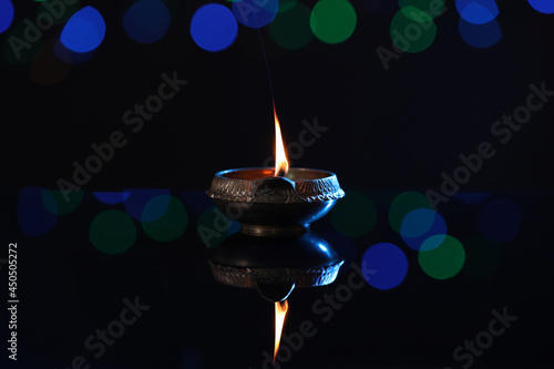 Lit diya on dark background with blurred lights. Diwali lamp photo