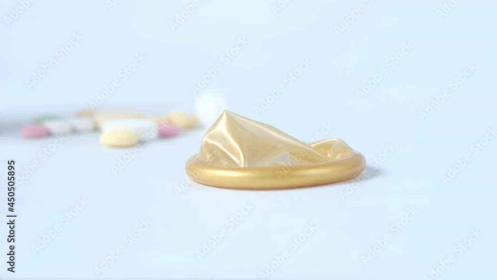 close up of condom and medical pills on white close up of condom and medical pills on white