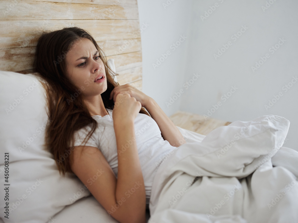 Angry woman lies in bed dissatisfied with high temperature Angry woman lies in bed dissatisfied with high temperature