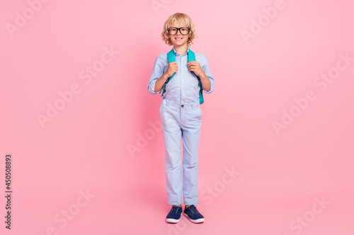 Photo of charming funny schoolboy wear blue shirt spectacles rucksack smiling isolated pink color background