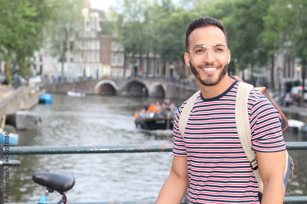 Young mixed race man enjoying a European cityscape view with a river Young mixed race man enjoying a European cityscape view with a river