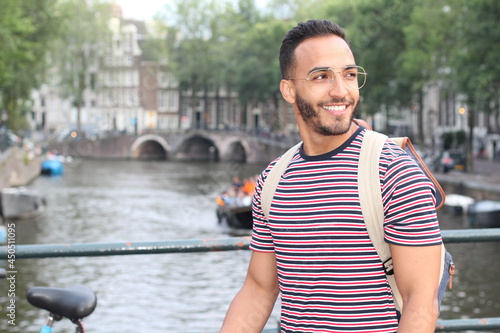 Young mixed race man enjoying a European cityscape view with a river
 photo
