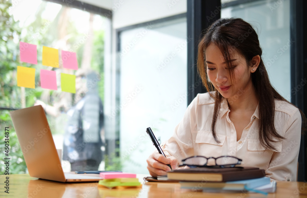 Young businesswoman working with laptop and making note on notebook. Young businesswoman working with laptop and making note on notebook.
