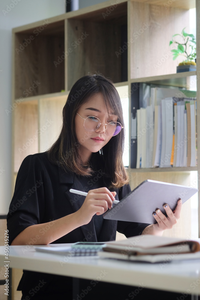 Businesswoman using digital tablet while sitting at her workplace. Businesswoman using digital tablet while sitting at her workplace.