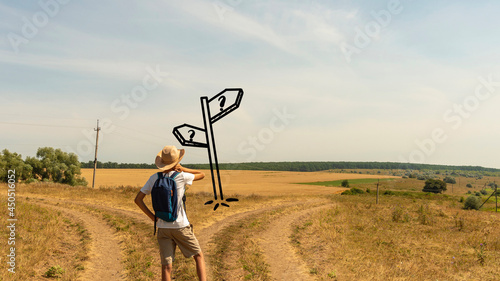 A young boy with a backpack stands at a fork in two roads at the road sign solving the problem of choosing the right path in life