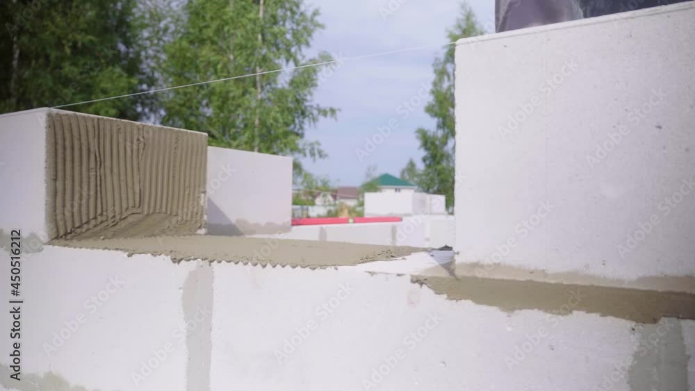 construction worker. a bricklayer laying a wall from a block, with a spatula for putty in the open air. He makes a close-up of concrete or an adhesive composition to glue the blocks together. construction worker. a bricklayer laying a wall from a block, with a spatula for putty in the open air. He makes a close-up of concrete or an adhesive composition to glue the blocks together.