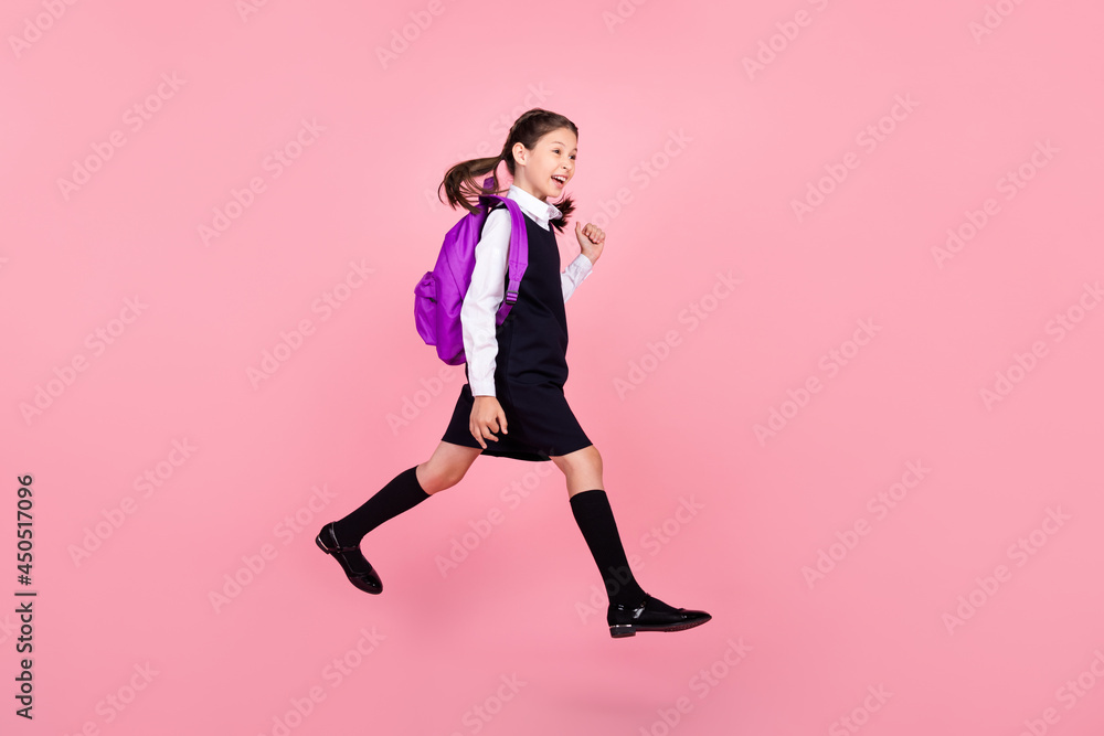 Full length body size photo schoolgirl jumping keeping backpack walking to school isolated pastel pink color background