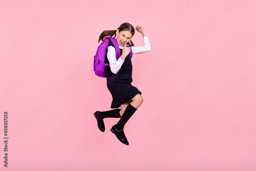 Full size profile side photo of young school girl happy positive smile jumper rejoice victory isolated over pink color background Full size profile side photo of young school girl happy positive smile jumper rejoice victory isolated over pink color background