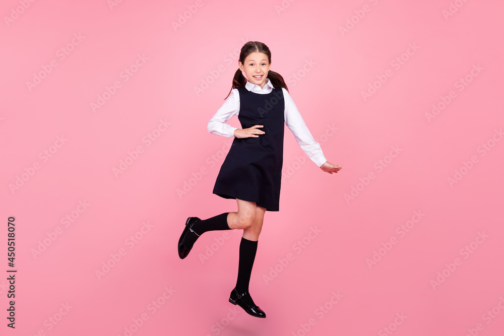 Full length body size photo schoolgirl jumping up wearing uniform confident isolated pastel pink color background Full length body size photo schoolgirl jumping up wearing uniform confident isolated pastel pink color background