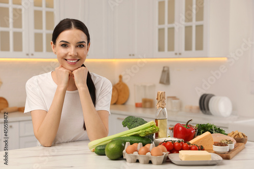 Happy woman with different products in kitchen. Keto diet