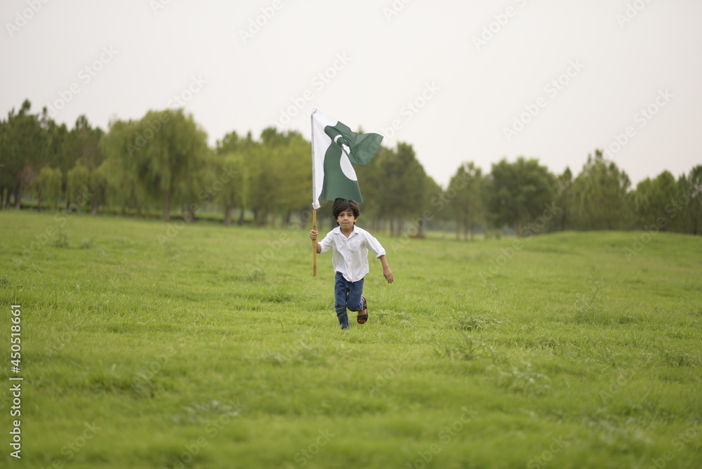 cheerful active little boy celebrating 14th of August, Pakistan Independence day with waving Pakistani flag. F-9 Park Islamabad, Pakistan.