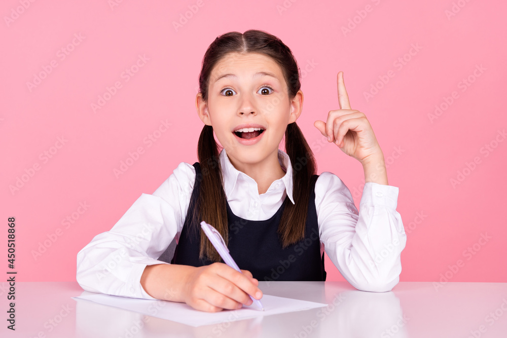 Photo portrait little girl with tails sitting at desk at school writing test got brilliant idea isolated pastel pink color background Photo portrait little girl with tails sitting at desk at school writing test got brilliant idea isolated pastel pink color background