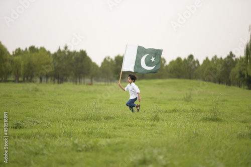 cheerful active little boy celebrating 14th of August, Pakistan Independence day with waving Pakistani flag. F-9 Park Islamabad, Pakistan.