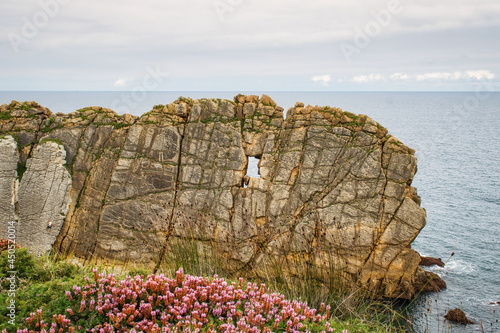 Hombre escalando una hermosa pared de roca con ventana natural en los urros de Liencres, provincia de Santander, España photo