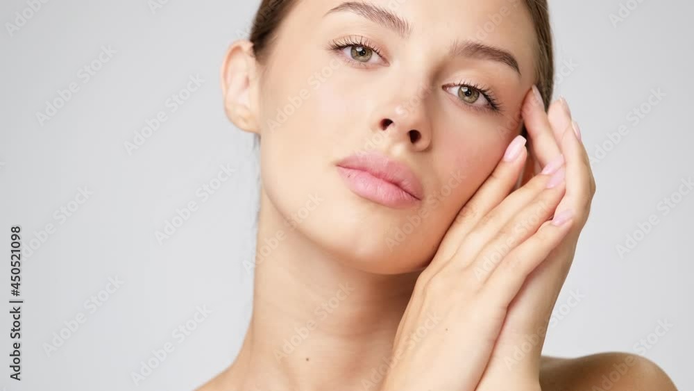 Beautiful Young Woman with Clean Fresh Skin standing over light grey background Beautiful Young Woman with Clean Fresh Skin standing over light grey background