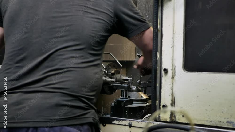 a worker puts parts in an automatic metal grinding machine in an industrial plant then the door is closed a worker puts parts in an automatic metal grinding machine in an industrial plant then the door is closed