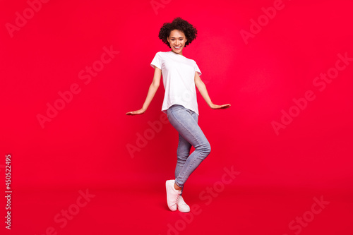 Full length body size photo smiling curly woman in casual clothes isolated bright red color background