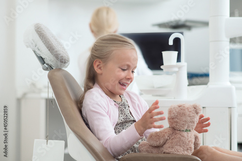 A small girl sitting in the dentist chair photo