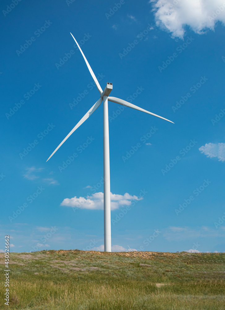 windmill on the background of the cloudy blue sky. Concept of alternative energy production from wind. Modern windmill with full-length blades. High quality photo windmill on the background of the cloudy blue sky. Concept of alternative energy production from wind. Modern windmill with full-length blades. High quality photo