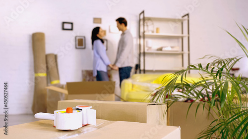 scotch tape on boxes near blurred couple holding hands in new home © LIGHTFIELD STUDIOS