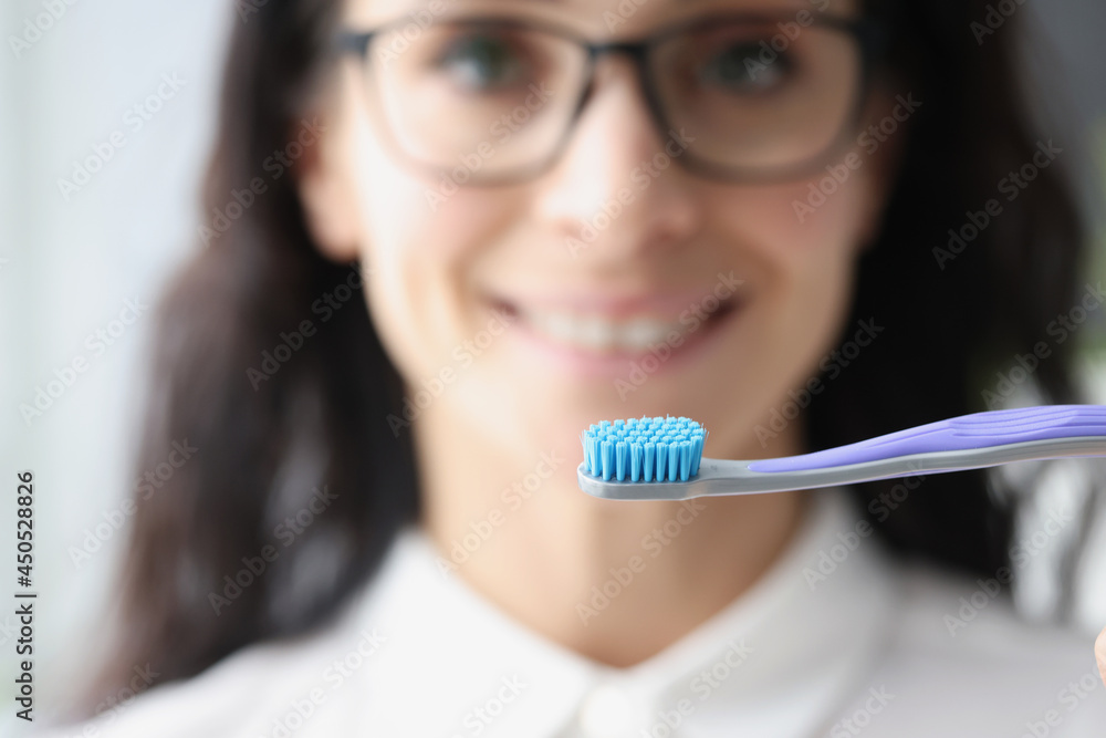 Young woman with glasses holding toothbrush closeup Young woman with glasses holding toothbrush closeup