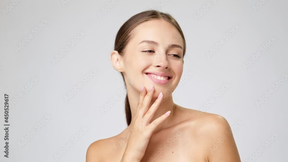Beautiful Young Woman with Clean Fresh Skin standing over light grey background Beautiful Young Woman with Clean Fresh Skin standing over light grey background