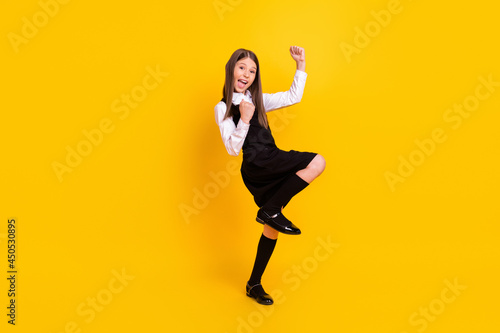 Full length body size photo schoolgirl in uniform gesturing like winner isolated bright yellow color background