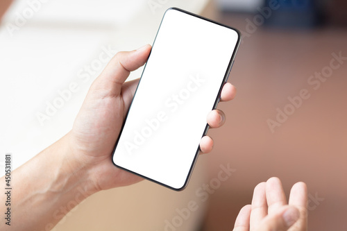 Hand holding and using smartphone with white blank on screen.