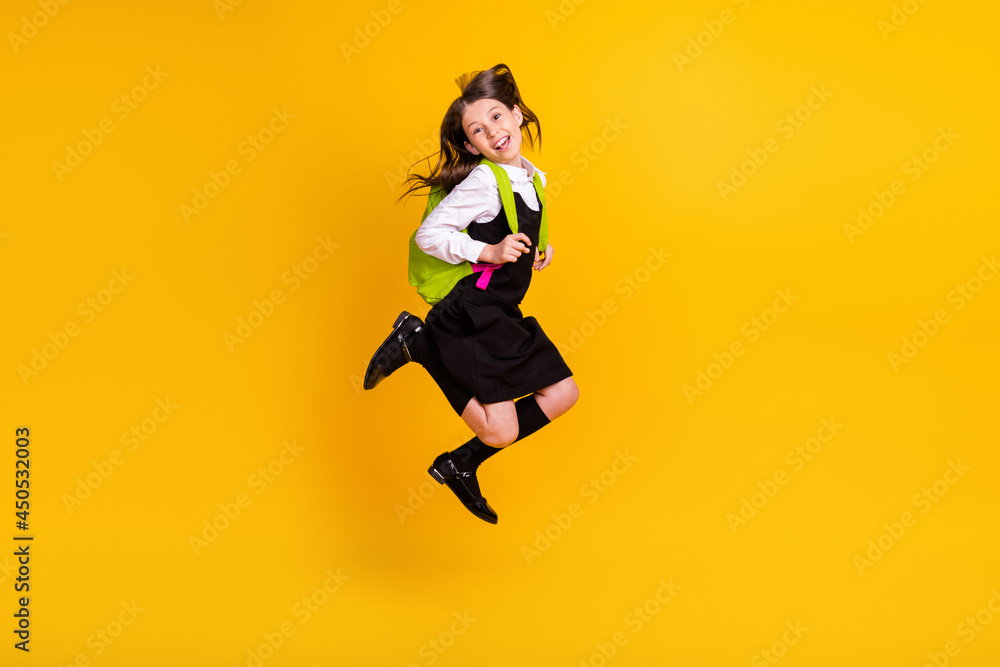 Full length body size photo schoolgirl jumping keeping rucksack laughing isolated vivid yellow color background