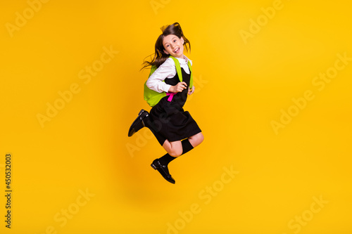 Fototapeta Naklejka Na Ścianę i Meble -  Full length body size photo schoolgirl jumping keeping rucksack laughing isolated vivid yellow color background