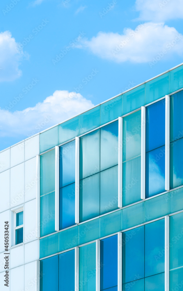 Low angle view of blue glass and white tile wall of modern office building against cloud and blue sky background in vertical frame Low angle view of blue glass and white tile wall of modern office building against cloud and blue sky background in vertical frame