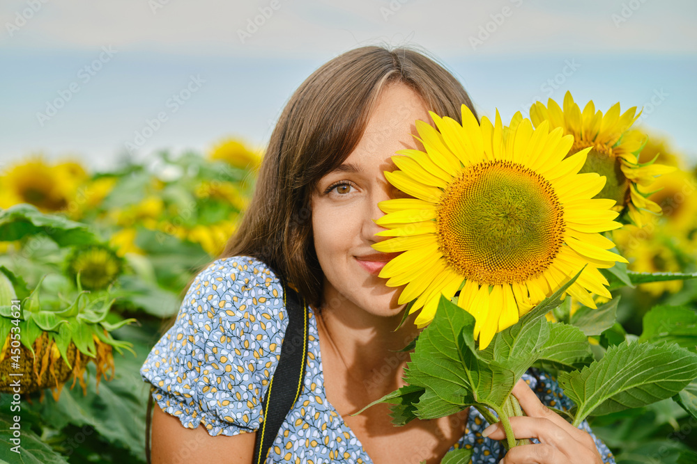 Joyful woman covers half of her face with sunflower Joyful woman covers half of her face with sunflower