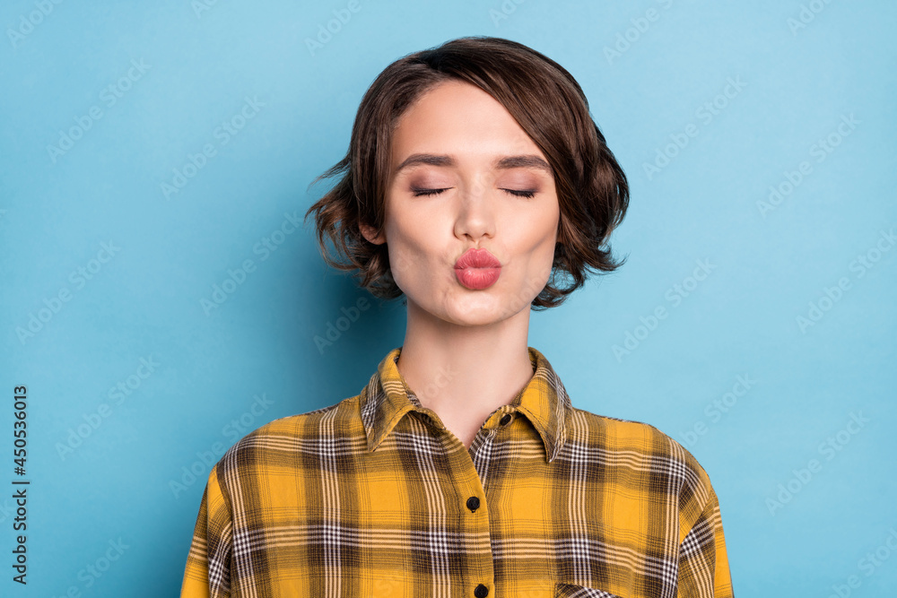 Photo of affectionate girl send air kiss close eyes wear checkered plaid shirt isolated blue color background