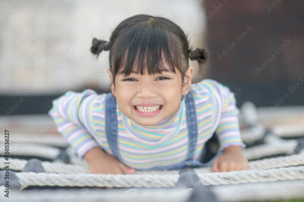 Cute children. Asian girl climbing in a rope playground structure at the adventure park Cute children. Asian girl climbing in a rope playground structure at the adventure park