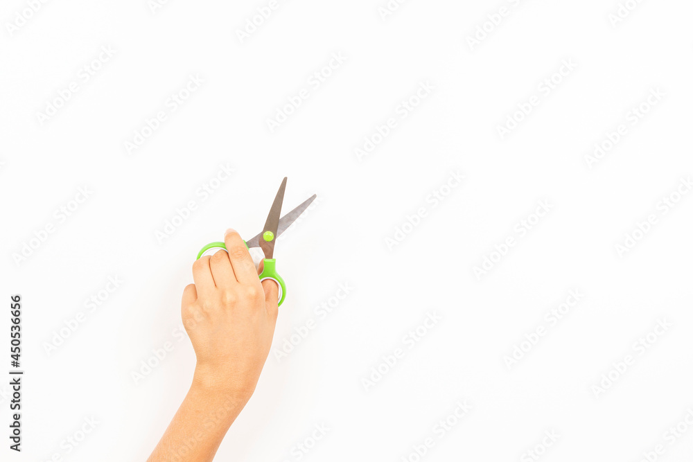 Kid left hand holding scissors over white background. Top view, copy space for text. Left Handers Day