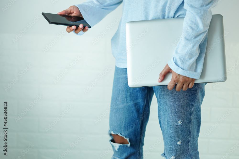 Fotka „Walk, holding a laptop, and mobile phone, at thigh level, in the